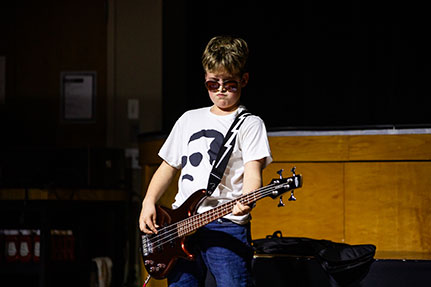 A boy playing a guitar in a talent show. Links to Gifts That Protect Your Assets
