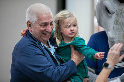 A grandparent holding his grandchild with a smile. Links to Gifts That Pay You Income